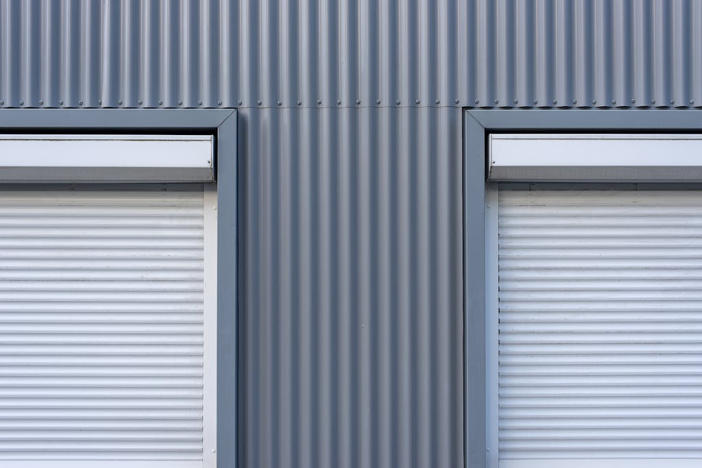 Dual industrial-style roller blinds on a corrugated metal wall for a sleek, modern look.